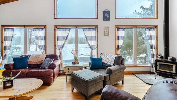 A cozy living room with a fireplace, large windows, and a comfortable seating area.