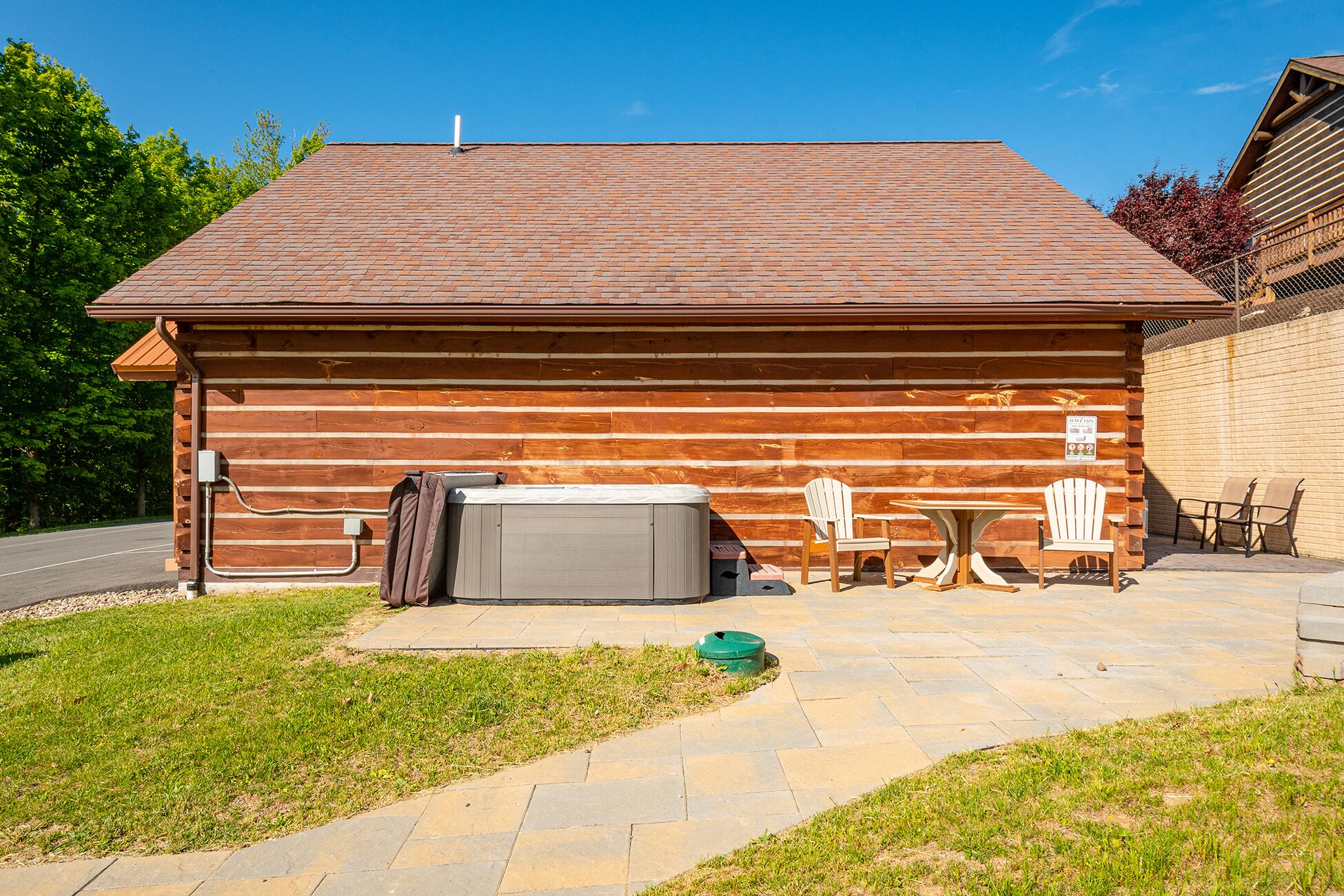 A wooden cabin with a tiled roof, a hot tub, and outdoor seating.
