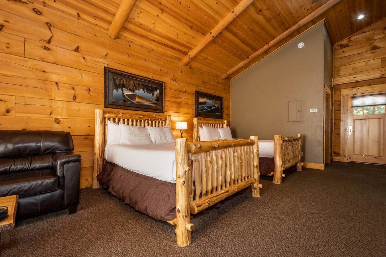 Una camera da letto in legno con un letto, una sedia e due quadri appesi al muro.