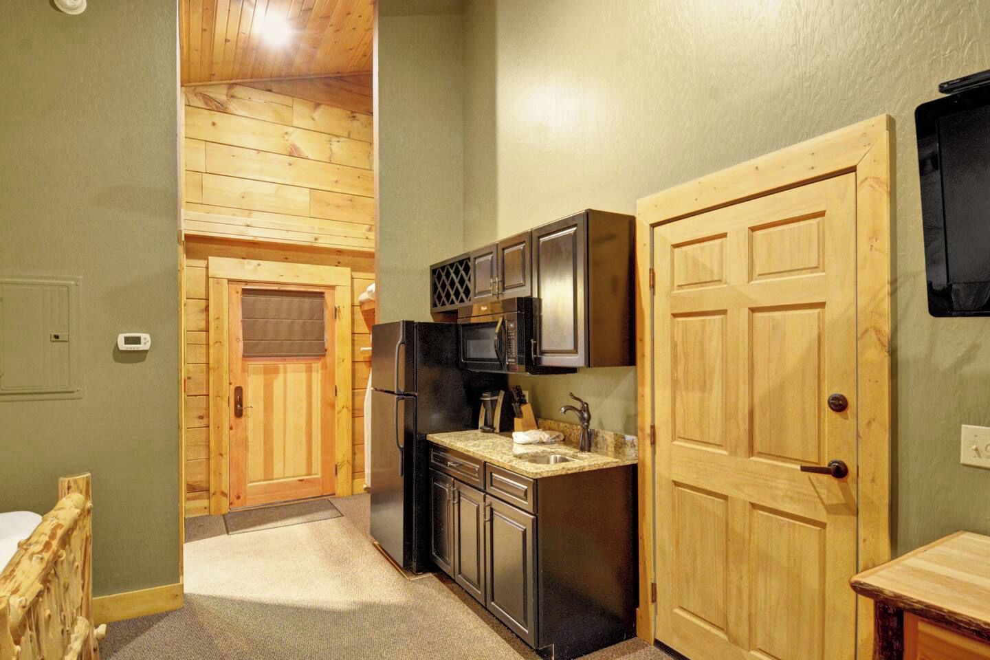 A compact kitchen with wooden cabinets, a refrigerator, and a microwave.