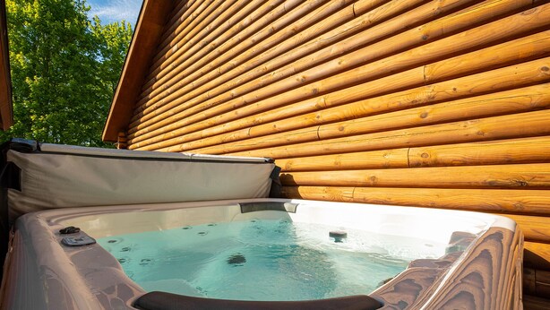 A hot tub with a wooden exterior wall and a covered seating area.