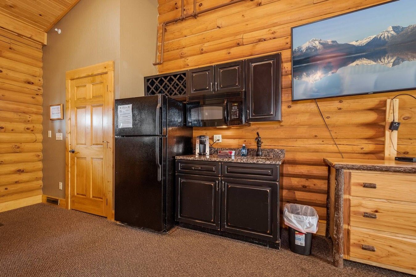 A compact kitchen with a refrigerator, microwave, and wooden cabinets.