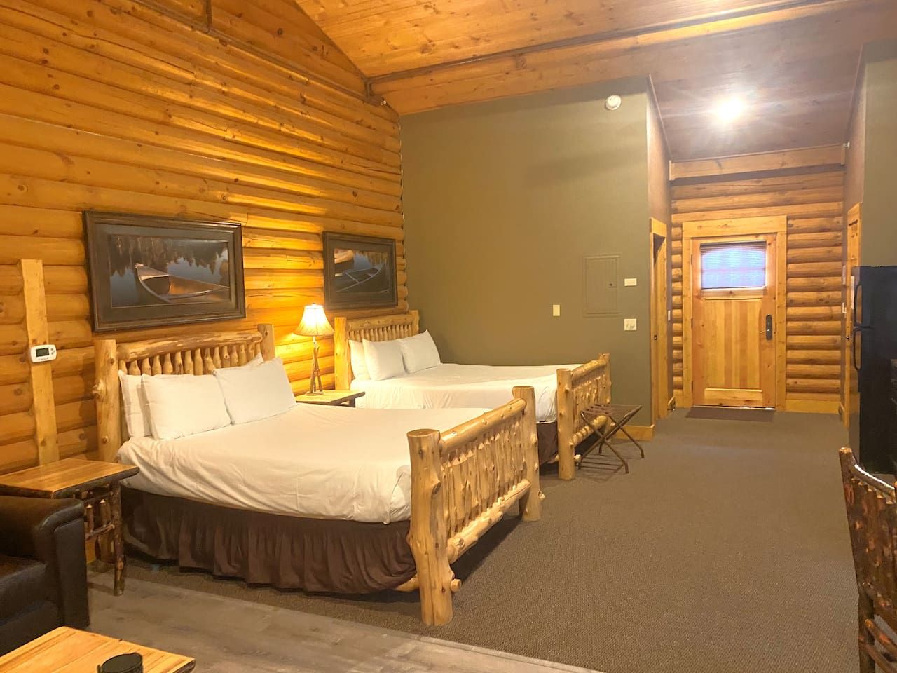 A log cabin-style room with two beds, a desk, and a television.