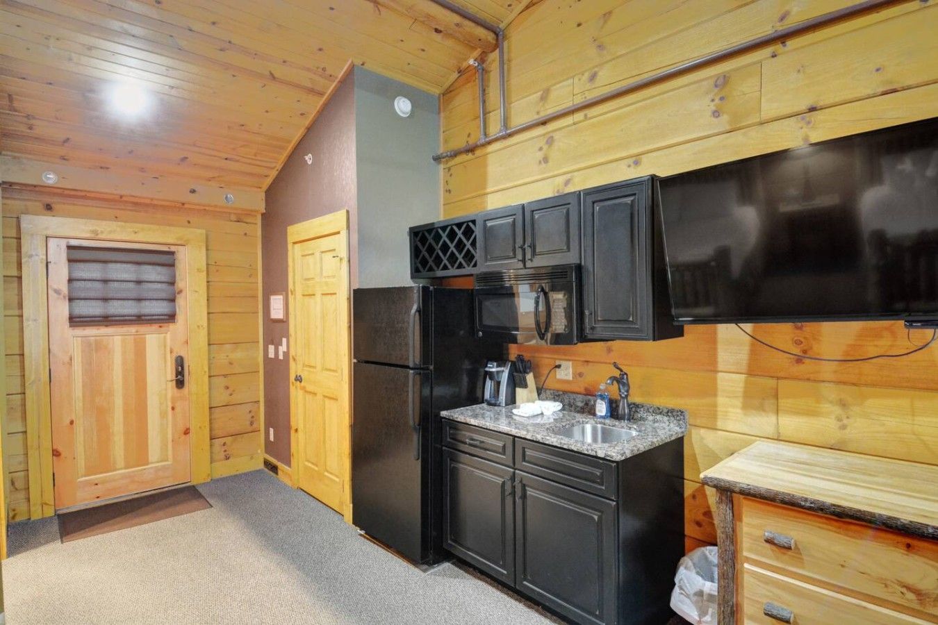 A compact kitchen with a refrigerator, microwave, and sink.