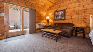 L’intérieur chaleureux d’un chalet avec un plafond en bois, un canapé, une table basse et une lampe.