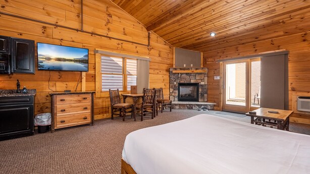 L’intérieur d’une cabane en rondins comprend un lit, une cheminée, un coin repas et une cuisine.