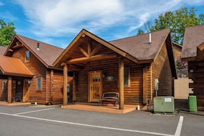 A log cabin-style building with a porch, a bench, and a welcome sign.