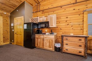 A compact kitchen with wooden cabinets, a refrigerator, a microwave, and a sink.