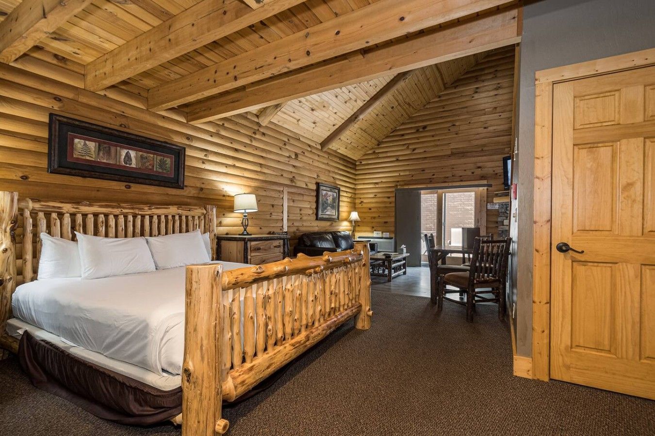 Une chambre aménagée dans un chalet en rondins, comprenant un lit, un bureau et un coin repas.