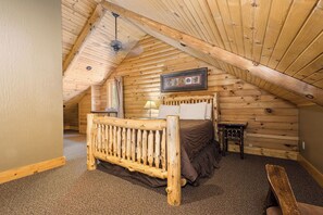 A cozy attic bedroom with a wooden bed, a nightstand, and a ceiling fan. - C45L - King, Queen, Kitchenette, Duplex (McHenry)