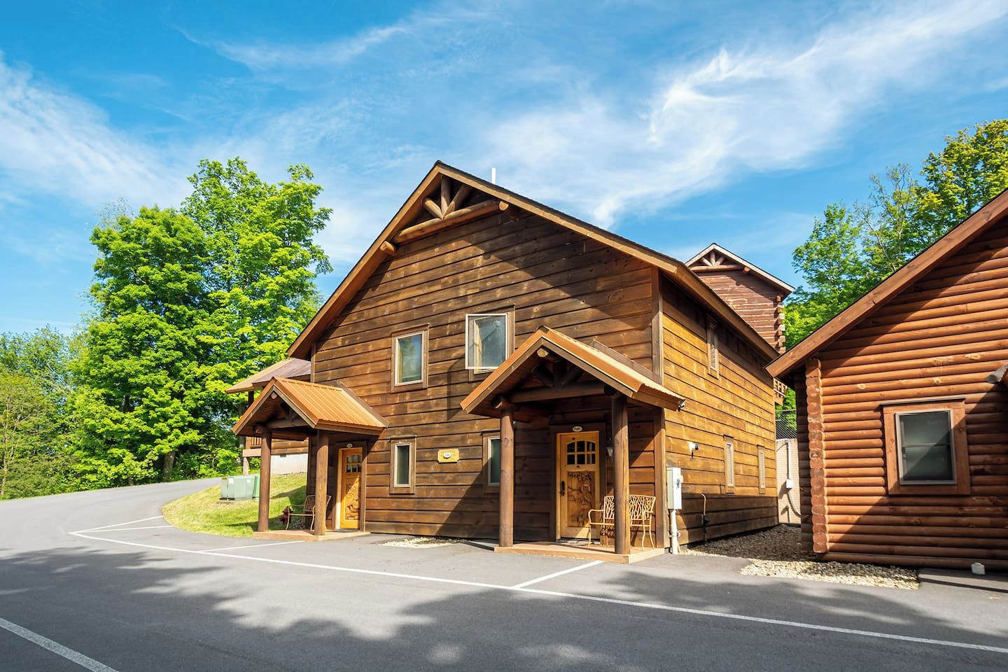 A two-story log cabin with a porch, a garage, and a driveway.