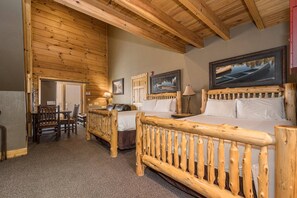 A wooden-furnished room with a bed, a desk, and a chair. - C46R - 3 Queen Beds, Duplex (McHenry)