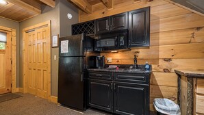 A compact kitchen with black appliances, wooden cabinets, and a granite countertop. - Mountainside Loft Cabin 46R (McHenry)