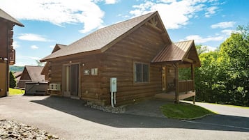 Een houten vakantiehuisje met een veranda, een welkomstbord en een brievenbus.