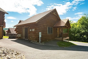 A wooden cabin with a porch, a welcome sign, and a mailbox.