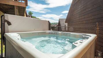 Een hottub met een houten terras en een omheind gebied.