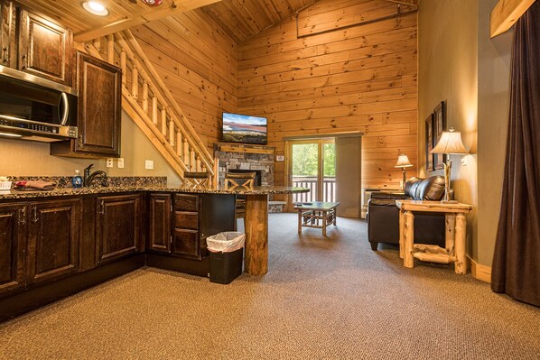 A log cabin interior with a kitchen, dining area, and a fireplace. - Mountainside Cabin 48, Family Suite-Hot Tub, Dog Friendly (McHenry)
