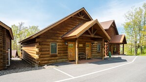 A log cabin with a porch and a sign that reads "Welcome."