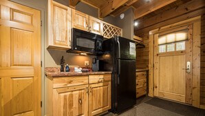 A kitchen with wooden cabinets, a black refrigerator, and a microwave.