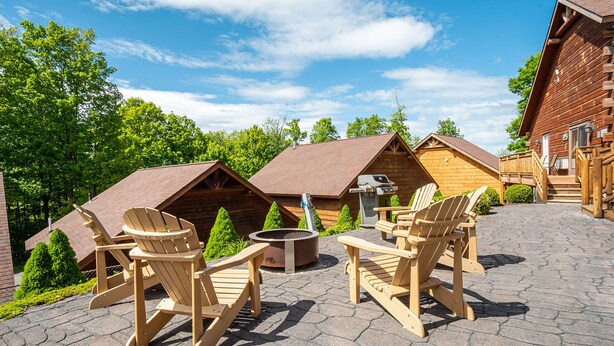 A wooden cabin with a fireplace and outdoor seating area.
