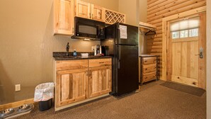 A compact kitchen with wooden cabinets, a black refrigerator, and a microwave. - Mountainside Cabin 51L (McHenry)
