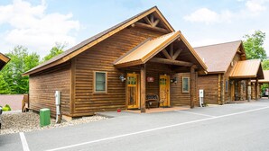 A wooden log cabin with a welcoming entrance, a bench outside, and a clear sky. - Mountainside Cabin 51L (McHenry)