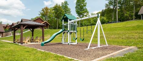A playground with a slide, swings, and a small shelter.