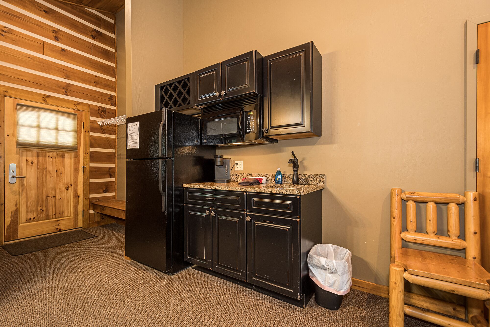 A compact kitchen with a refrigerator, microwave, and wooden cabinets.