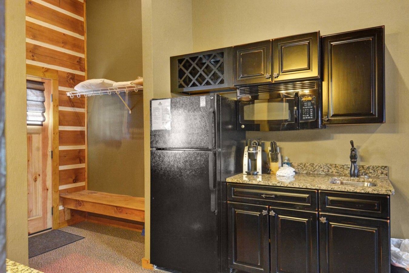 A compact kitchen with a refrigerator, microwave, and a sink.