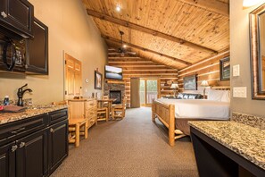 L’intérieur d’une cabane en rondins comprend une cuisine, un coin repas et une chambre à coucher.