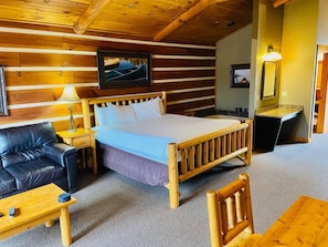 A cozy room with a bed, a sofa, a small table, and a chair.