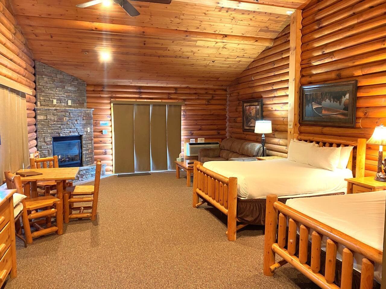 L’intérieur d’une cabane en rondins, avec une cheminée, un lit, une table à manger et un canapé.