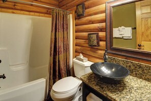 A bathroom with a shower curtain, toilet, sink, and a mirror.