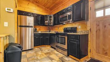 A kitchen with black cabinets, stainless steel appliances, and a granite countertop.