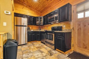 A kitchen with black cabinets, stainless steel appliances, and a granite countertop.