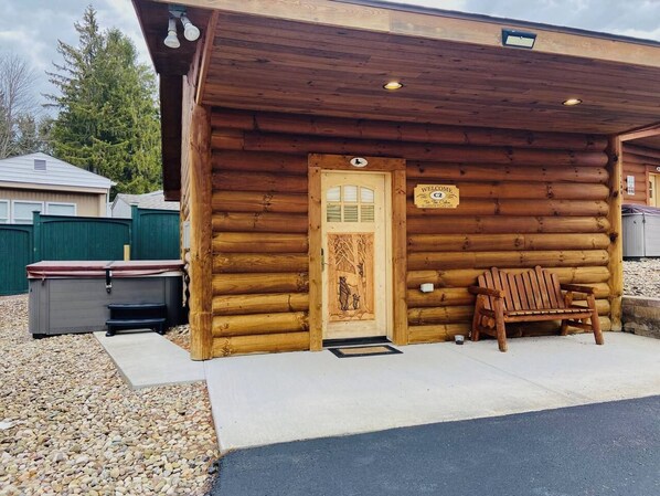 A log cabin with a wooden door, a bench, and a small outdoor seating area.