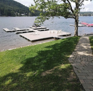A lakeside dock with floating platforms, a grassy area, and a paved walkway. - C3 - 2 Queen, Lakefront, Hot Tub, Pet Friendly (McHenry)