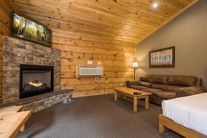 A cozy room with a fireplace, a couch, a bed, and a painting on the wall.