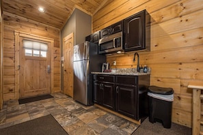 A compact kitchen with wooden walls, a refrigerator, a microwave, and a sink. - C3 - 2 Queen, Lakefront, Hot Tub, Pet Friendly (McHenry)