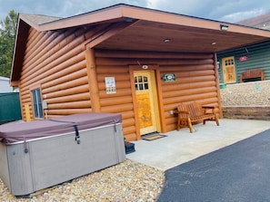 A log cabin with a covered porch, a bench, and a small outdoor seating area.