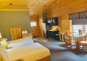 A cabin with two beds, a dining area, and a kitchen.