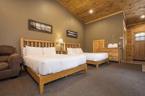 A room with two wooden beds, a brown leather chair, a wooden dresser, and a door leading outside.