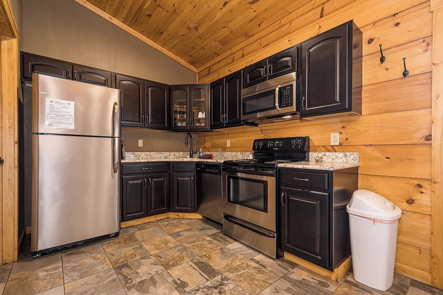 A compact kitchen with dark cabinets, stainless appliances, and a granite countertop.