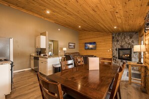 Une cuisine spacieuse avec des meubles en bois, un coin repas doté d’une grande table en bois et une cheminée en pierre.