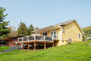 Une maison jaune à deux étages, dotée d’un porche et, sur sa gauche, d’une petite construction ressemblant à un chalet.