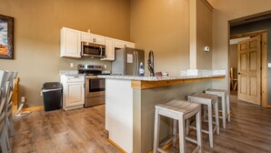 A kitchen with a central island, stainless steel appliances, and a wooden floor.