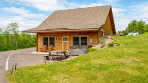 A wooden lodge with a pitched roof, a picnic table, and a bench outside.