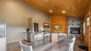 A spacious kitchen with a dining area, a stone fireplace, and a large window.