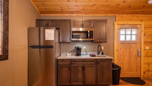 A compact kitchen with a stainless steel refrigerator, a microwave, and a coffee maker.