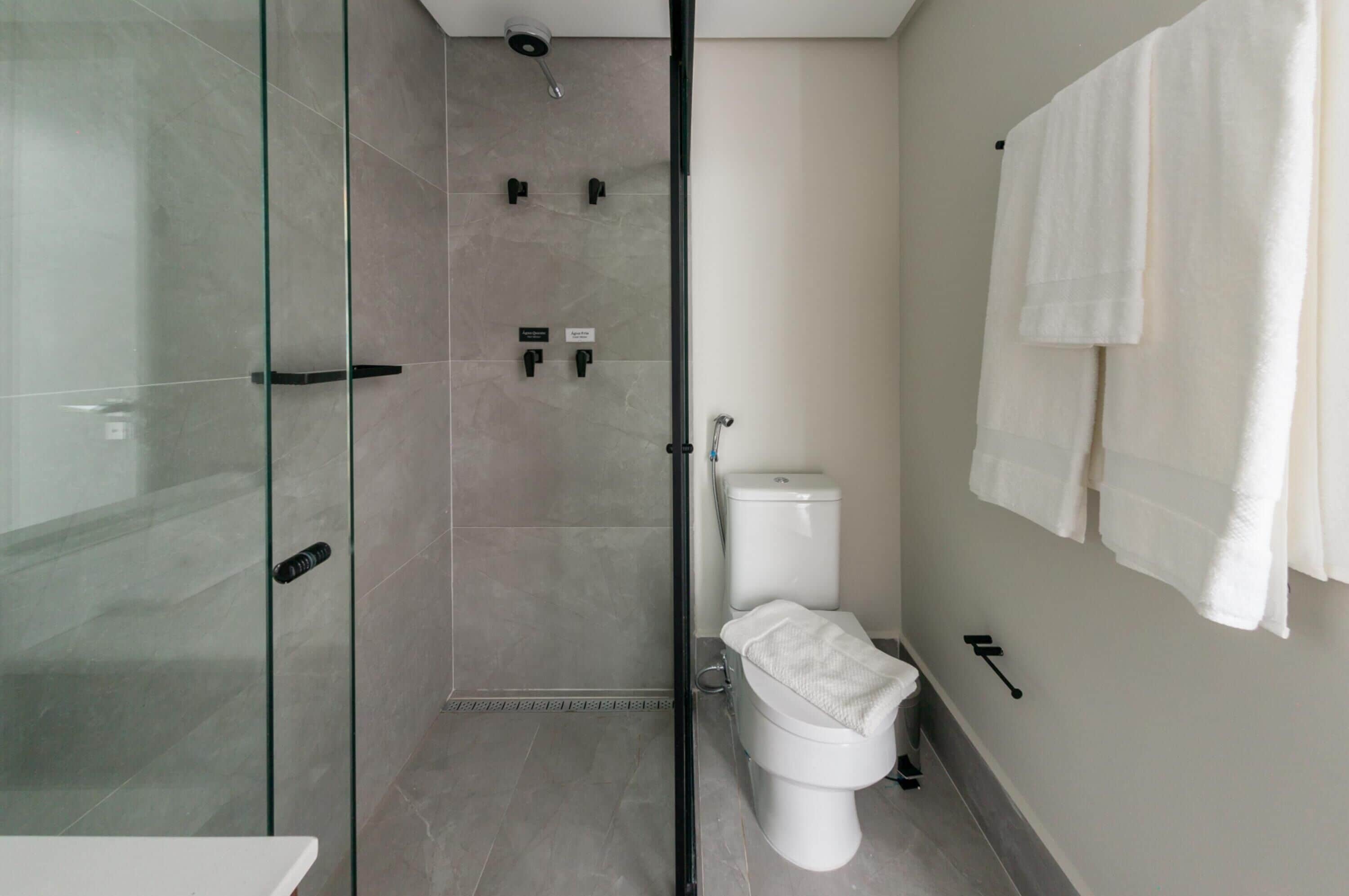 Un baño moderno con cabina de ducha de vidrio, un inodoro y un perchero para toallas.